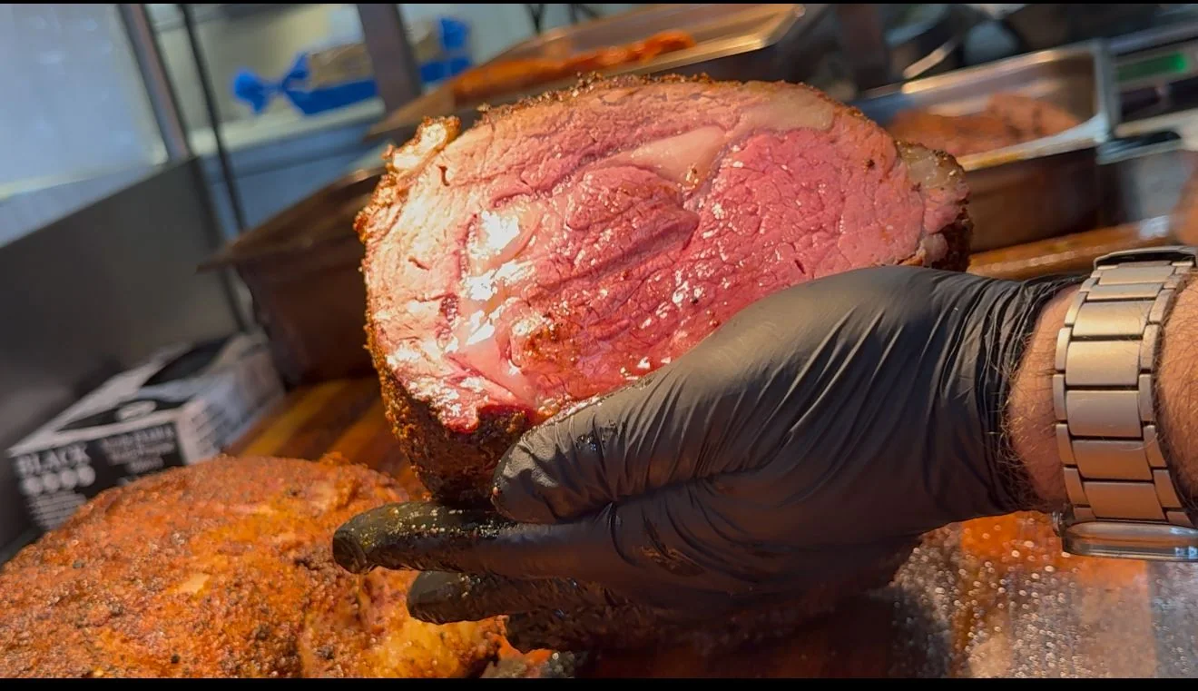 A gloved cook holding a freshly carved roast above the cutting board