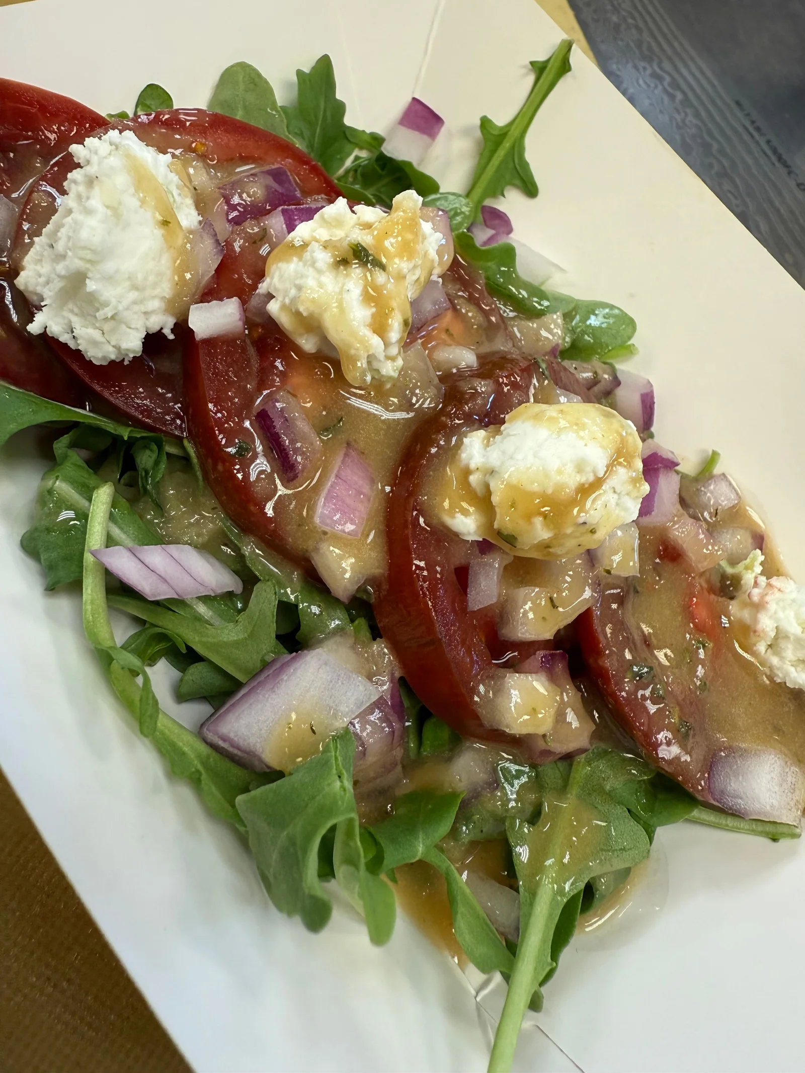 A leafy salad topped with tomatoes, onion and crumbled cheese