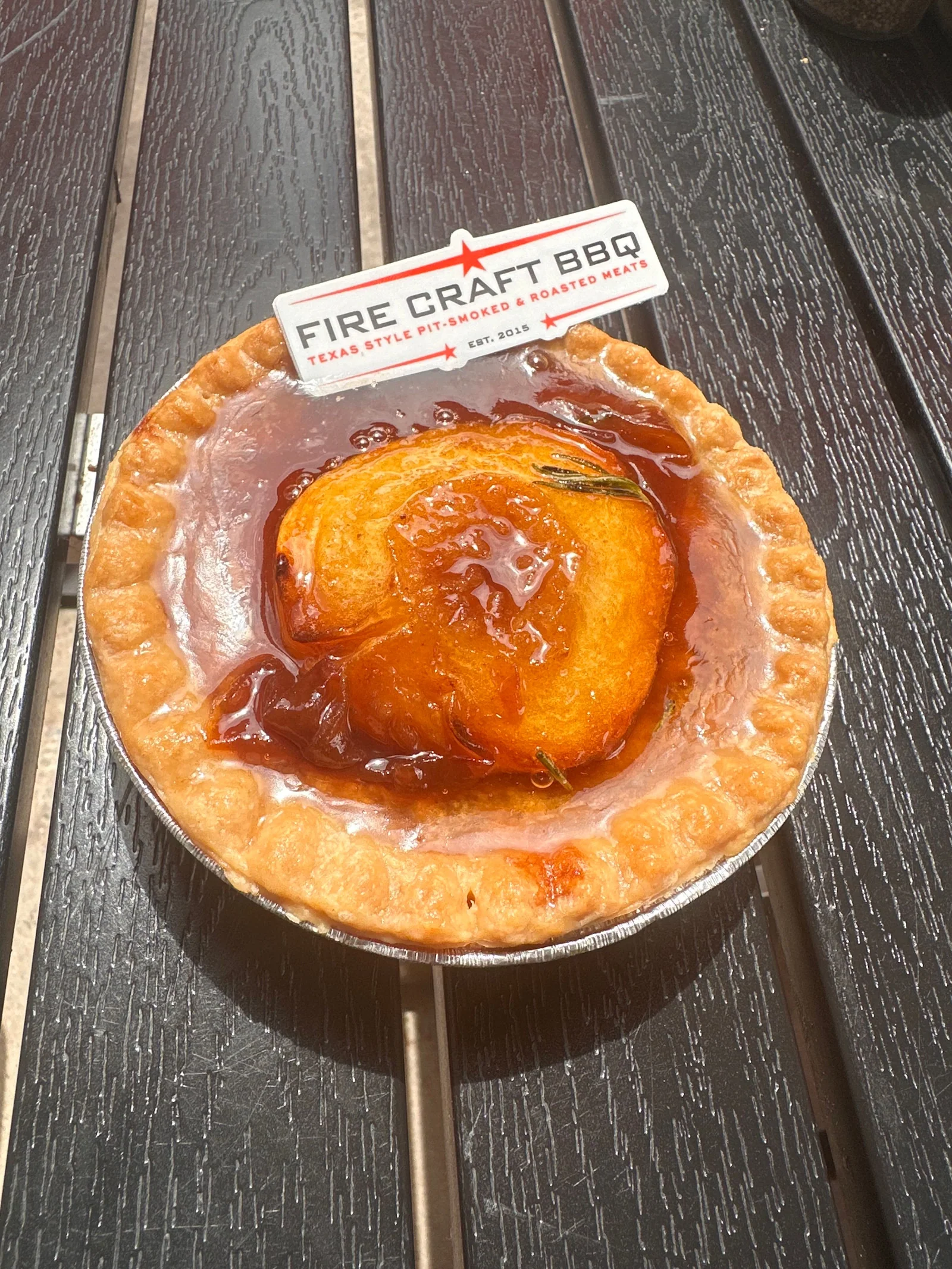 An individual tart topped with a baked peach and a Fire Craft flag