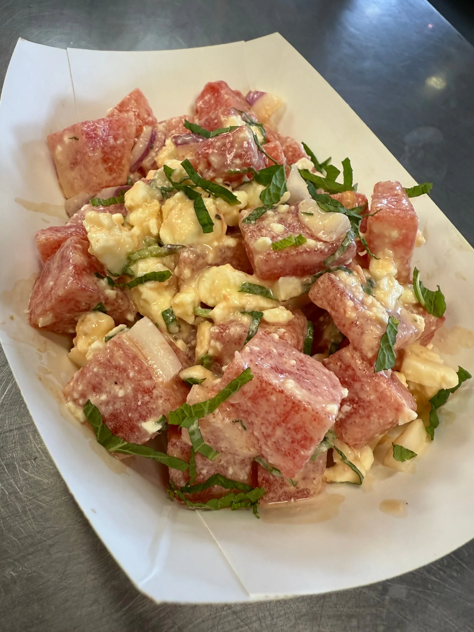 Watermelon salad with crumbled cheese, herbs and a creamy dressing