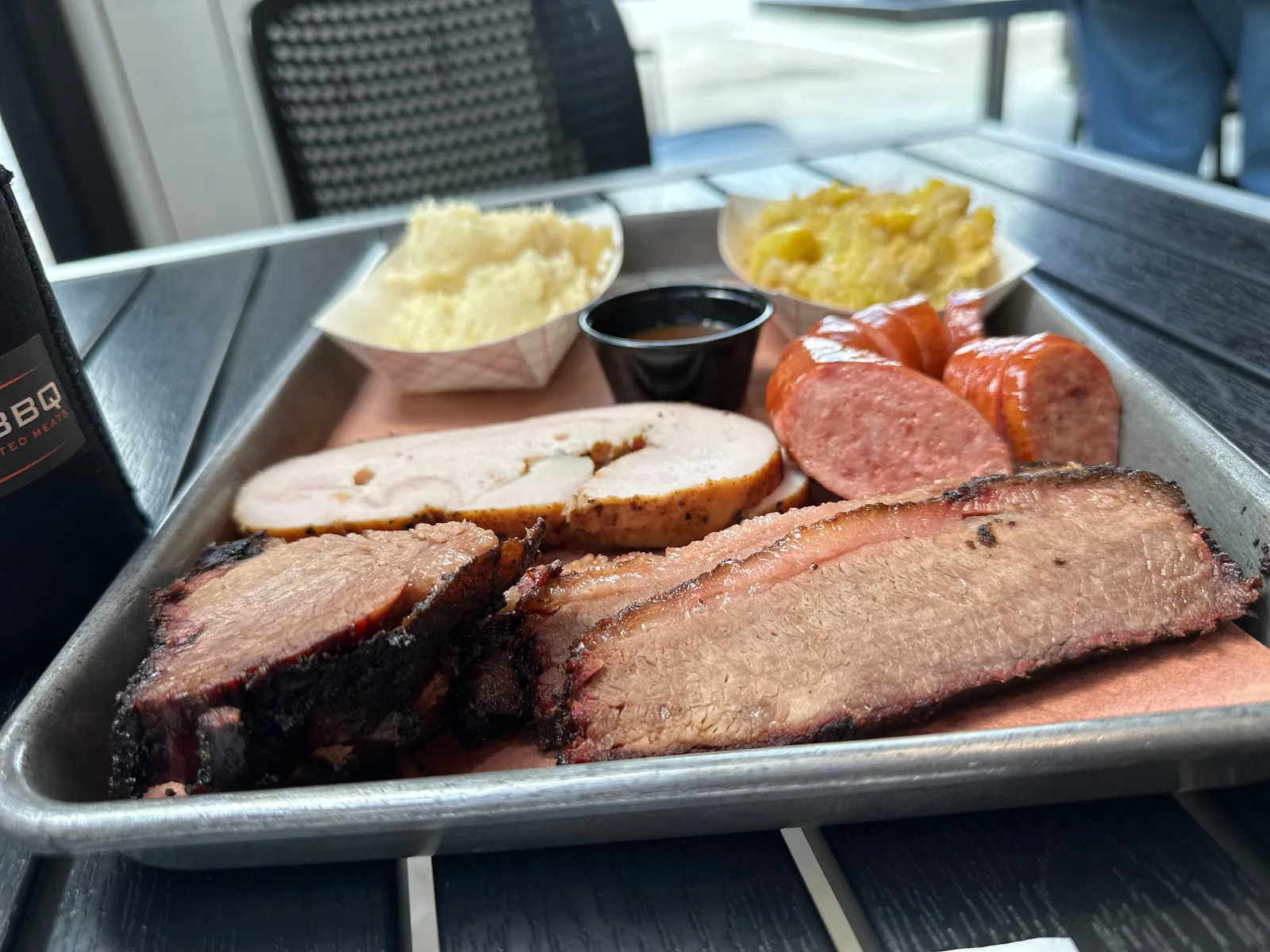 A Fire Craft tray of sliced smoked meats, sausage and sides